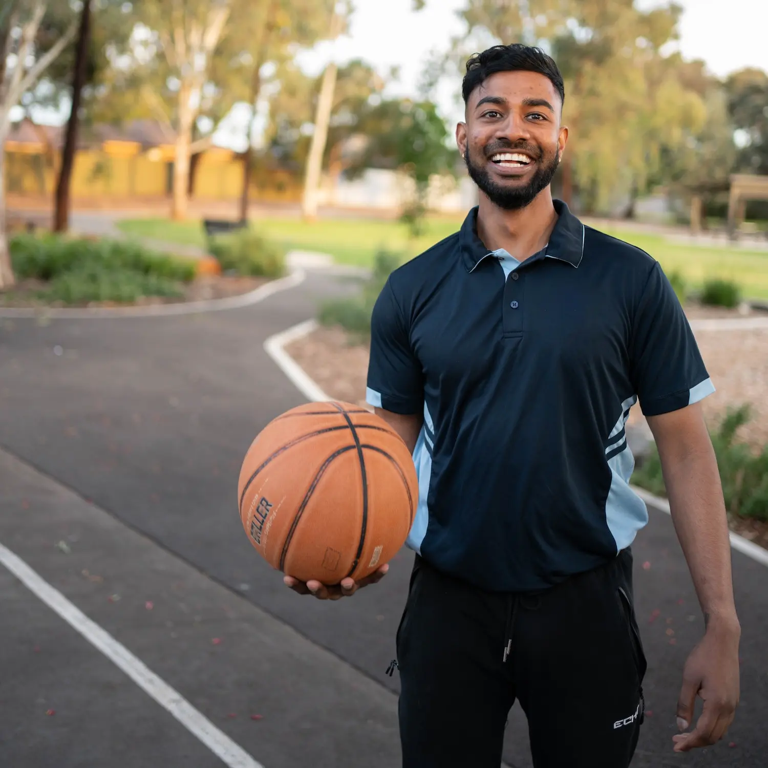 Kas smiling whilst holding a basketball.